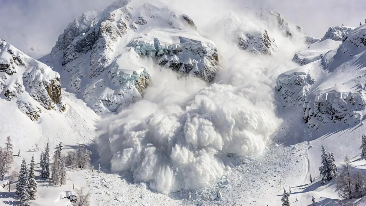 Montagne enneigée avec une avalanche dévalant un versant, illustrant les risques en altitude